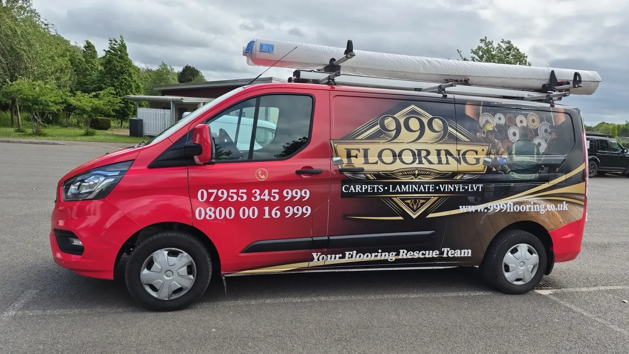 999 Flooring branded red and black flooring service van carrying carpet rolls